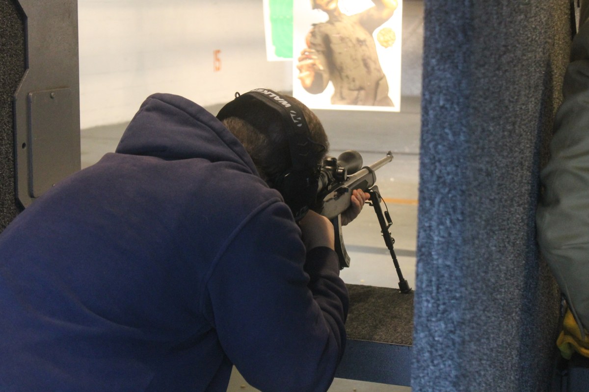 Shooter using hearing protection in a partitioned indoor rifle range