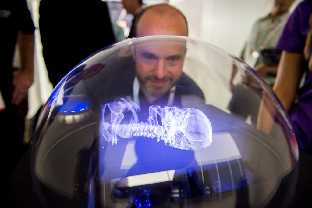 Visitor examining a volumetric skull visualization on a VX1 display at a technology demonstration